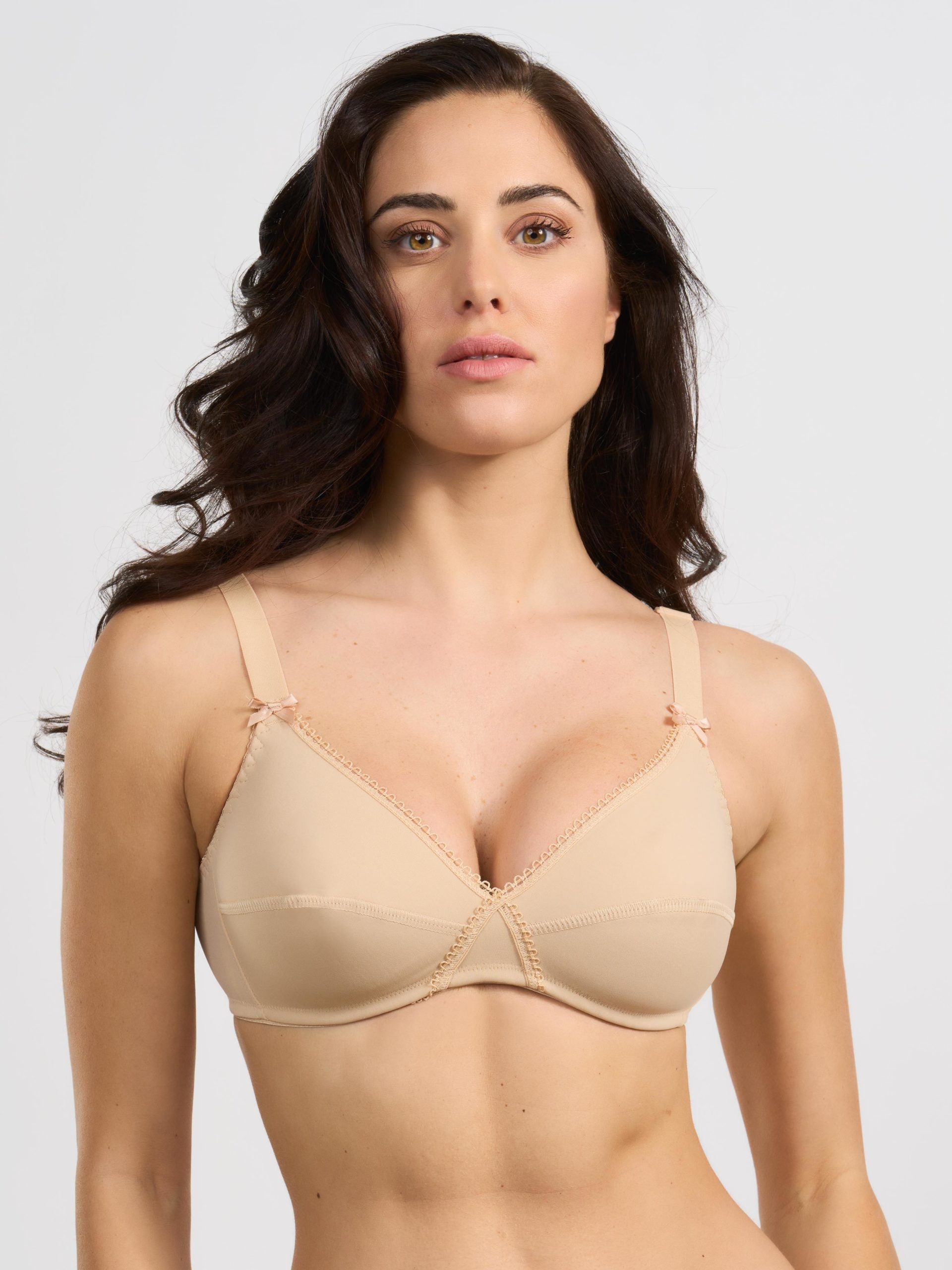 Reggiseno in tessuto elasticizzato color nudo con spalline regolabili e fiocchetto decorativo.